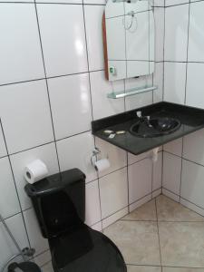 a bathroom with a black toilet and a sink at Pousada da Paz in Itacaré