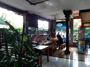 a group of people sitting at tables in a restaurant at Kembar Inn Padangbai in Padangbai