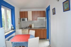 a kitchen with a red table and chairs in a room at Villa Verde Apartments and Rooms in Premantura