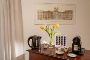 una mesa con cafetera y un jarrón de flores en Daplace - Augusta Apartment, en Roma