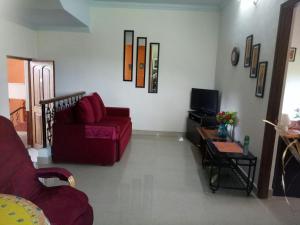a living room with a red couch and a tv at Saldanha Kyle gardens in Calangute