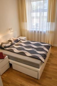 uma cama com um edredão preto e branco e uma janela em Studio 59 em Kaunas