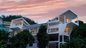 un edificio blanco con árboles frente a la puesta de sol en Serenity Villa, en Bang Tao Beach