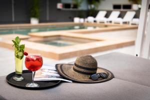um chapéu e uma bebida numa mesa ao lado de uma piscina em Grand Hotel and Apartments Townsville em Townsville