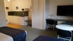 a hotel room with a desk and a table and a television at Ararat Southern Cross Motor Inn in Ararat