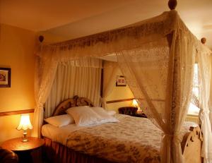1 dormitorio con cama con dosel y cortinas en Chequers Inn Hotel en Forest Row