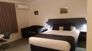 a hotel room with a large bed and a chair at Ararat Southern Cross Motor Inn in Ararat
