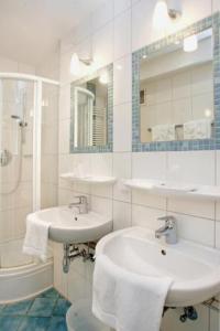 a white bathroom with two sinks and a shower at Rheinland Hotel in Bonn