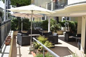 patio z krzesłami i parasolem w obiekcie Hotel Perla Verde w Rimini