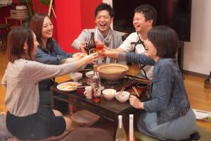 a group of people sitting around a table drinking beer at Riverside TABI-NE in Kanazawa