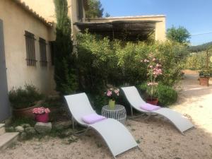 two white chairs sitting in a yard with flowers at La Petite Garrigue in Mérindol