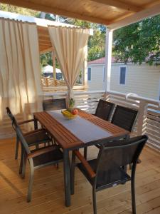 a wooden table and chairs on a patio at Mobile Home Seahorse Camp Soline in Biograd na Moru