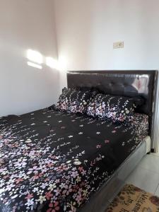 a bed with a black bedspread with flowers on it at Villa Puncak Garuda A5 in Batu