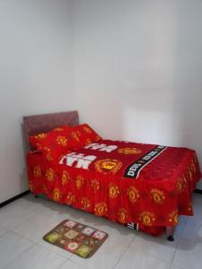 een bed met een rode deken en twee matten op de vloer bij Villa Puncak Garuda A5 in Batu