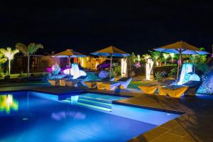 a swimming pool with chairs and umbrellas at night at Eden Appartel in Koné +7 photos