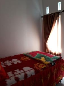 a bed with a red blanket and a window at Villa Puncak Garuda A5 in Batu