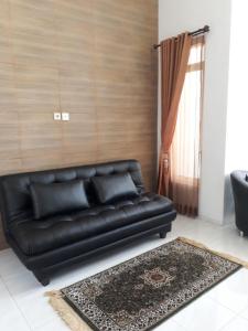 Villa Puncak Garuda A5 في باتو: أريكة جلدية سوداء في غرفة معيشة مع نافذة