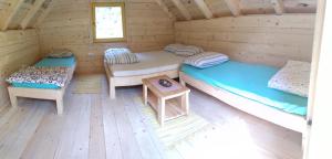una habitación con 2 camas y una mesa en una cabaña de madera en Camp Vrbas en Rekavice