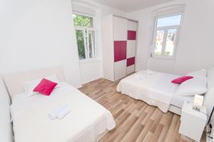 a white room with two beds and two windows at City Core Apartment in Split