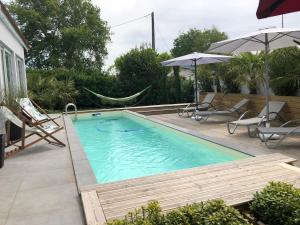 een zwembad met een hangmat en stoelen en een huis bij La ravissante ferretcapienne in Lège-Cap-Ferret