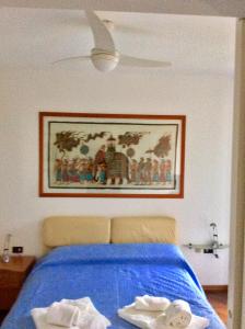 a bedroom with a blue bed with a picture on the wall at La Meridiana sul Lago in Abbadia Lariana
