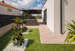een tuin met gras en een patio met een parasol bij Apartment Flawless in Trogir