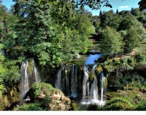 a group of waterfalls in a forest with trees at Guest House Iva in Slunj