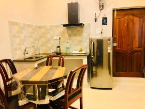 a kitchen with a table and a stainless steel refrigerator at Le Windfall Luxury in Puducherry