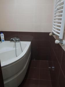 a bathroom with a white tub and brown tiles at Isani Panorama in Tbilisi City
