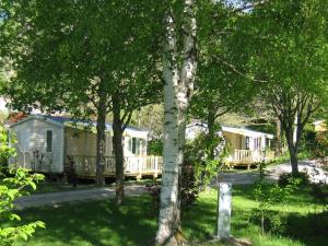 two mobile homes in a yard with trees at Le mobilhome Chez Camille in Veynes