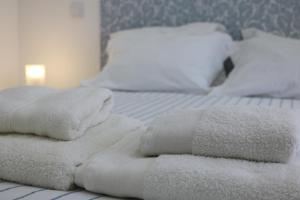 Un par de toallas blancas están apiladas en una cama. en Casa Malpique, en Albufeira