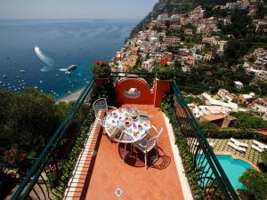 a balcony with a table and chairs on the side of a city at Villa dei Fisici Positano in Positano