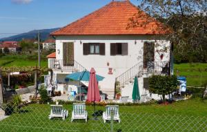 a house with chairs and umbrellas in front of it at Casa das Lages in Paredes de Coura