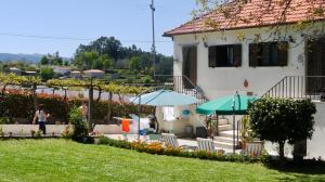 a house with two umbrellas and a yard at Casa das Lages in Paredes de Coura