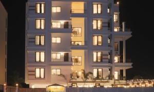 那格浦尔Treebo Chalets, Nagpur Airport的一座高大的白色建筑,晚上有明亮的窗户