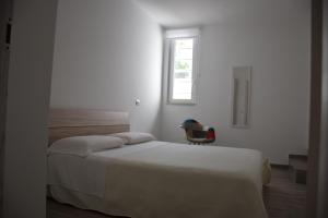 a bedroom with a bed and a chair under a window at Dimora Santa Caterina in Conversano