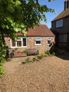 una casa de ladrillo con un banco delante de ella en The Old Barn Annexe, en West Runton