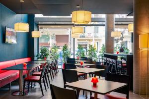 a dining room with tables and chairs and windows at Ibis Barcelona Centro (Sagrada Familia) in Barcelona