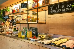 
a counter with a variety of food items on it at Ibis Barcelona Centro (Sagrada Familia) in Barcelona
