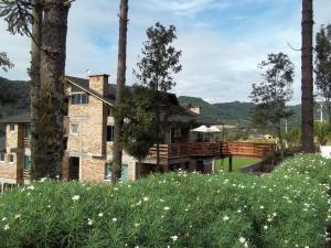 une maison avec une terrasse et une cour fleurie dans l'établissement Bina's Haus Pousada, Cafeteria e Atelier, à Nova Petrópolis