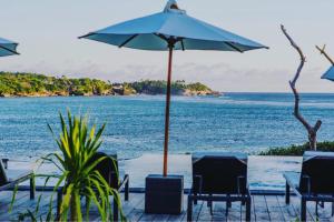 a beach with chairs and an umbrella and the ocean at Lembongan Seaview in Nusa Lembongan