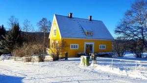 a yellow house in the snow with a fence at Det Gule Huset Hurdal in Hurdal