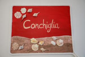 a red sign with shells on a beach at La casa del pescatore in Oliveri