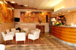 una sala de espera con sillas blancas y un bar en Hotel Da Franco, en Nogarole Rocca