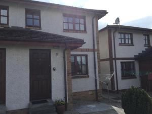 een wit huis met een bruine deur en ramen bij Culloden Apartment Free Parking in Inverness