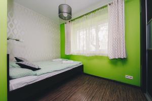ワルシャワにあるShortStayPoland Solidarnosci (B8)の緑の壁のベッド1台、窓が備わる客室です。