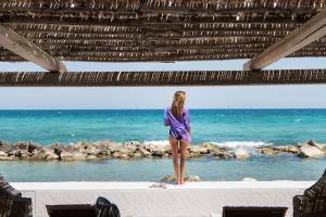 a woman in a purple dress standing on the beach at La Peschiera in Monopoli