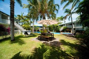 a picnic table with an umbrella next to a pool at Mango House Resort in Airlie Beach