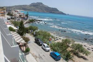Creta Mare Hotel في بلاكاس: اطلالة على شاطئ فيه سيارات تقف على شارع