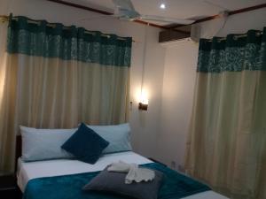 a bedroom with two beds with blue pillows at Agnes Cottage in La Digue